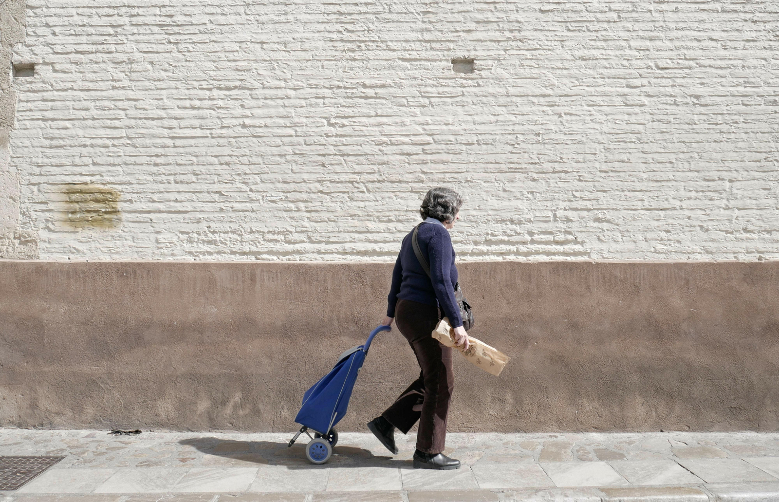 Una señora mayor pasa por delante de la fachada de Santa Catalina de Zafra