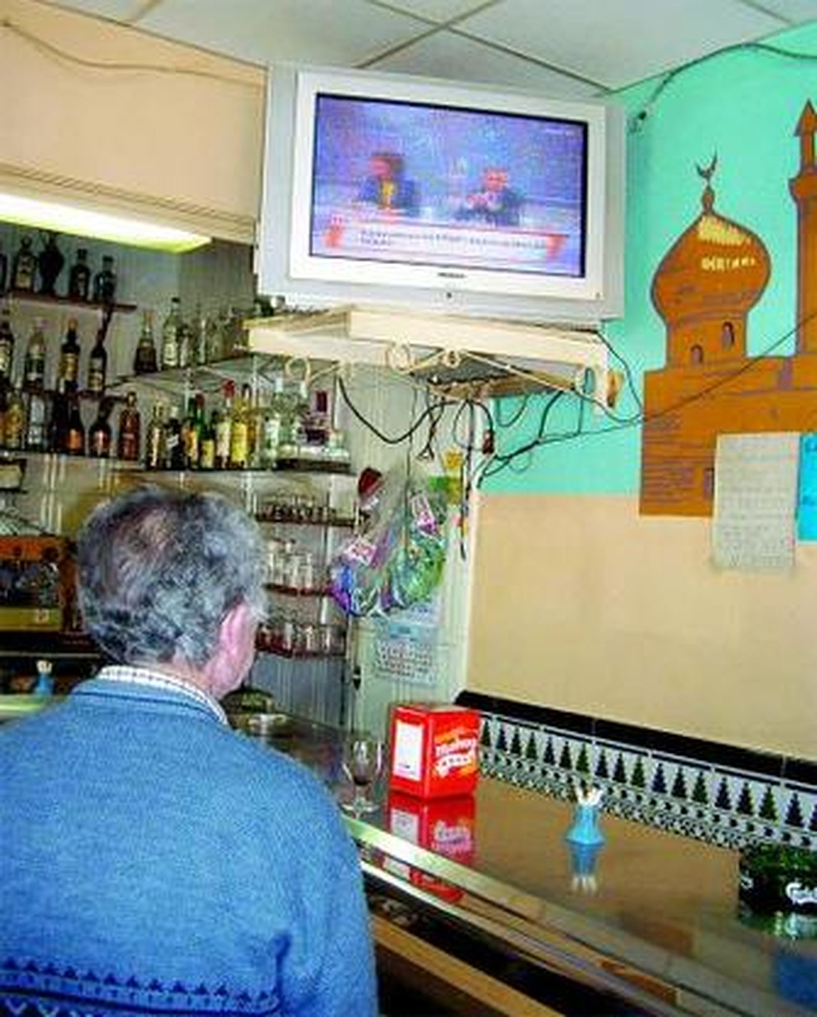 Un hombre intenta ver la televisión en un bar, pero la imagen es pésima.