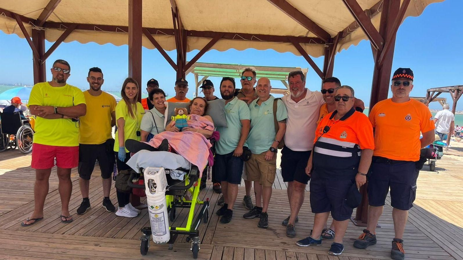 La mujer con movilidad reducida, junto al equipo que le ayudó a visitar la playa de Valdelagrana.