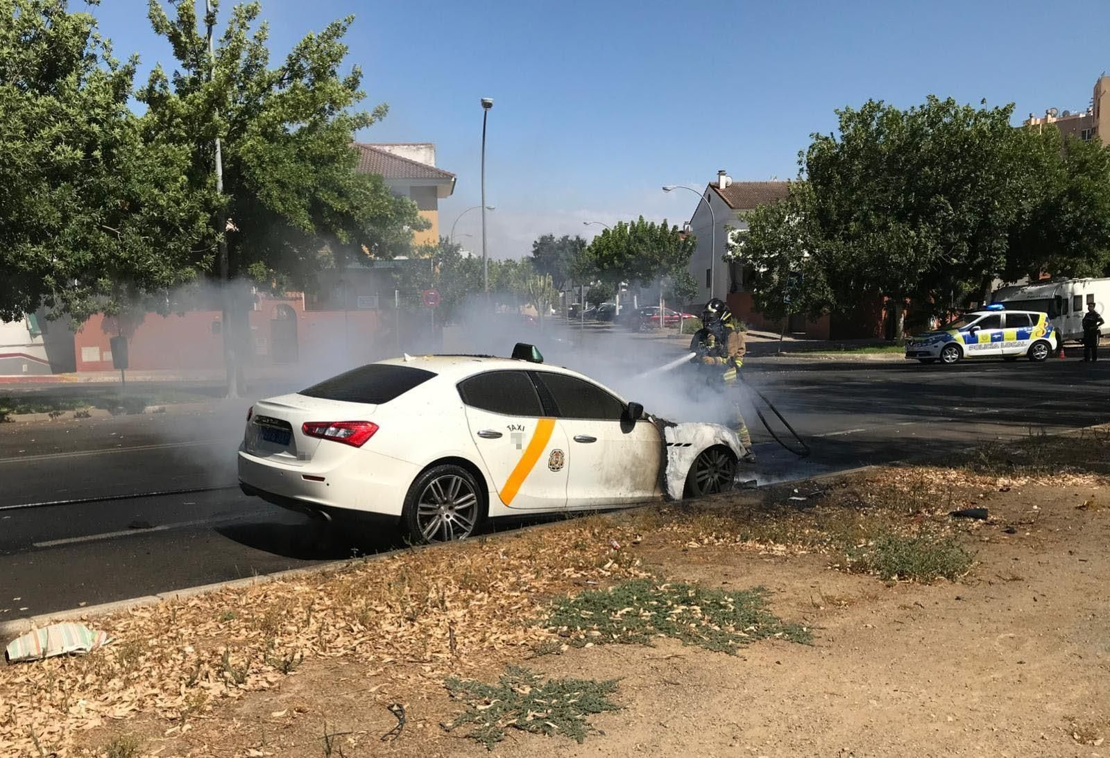 Un bombero apaga el fuego del Maserati.