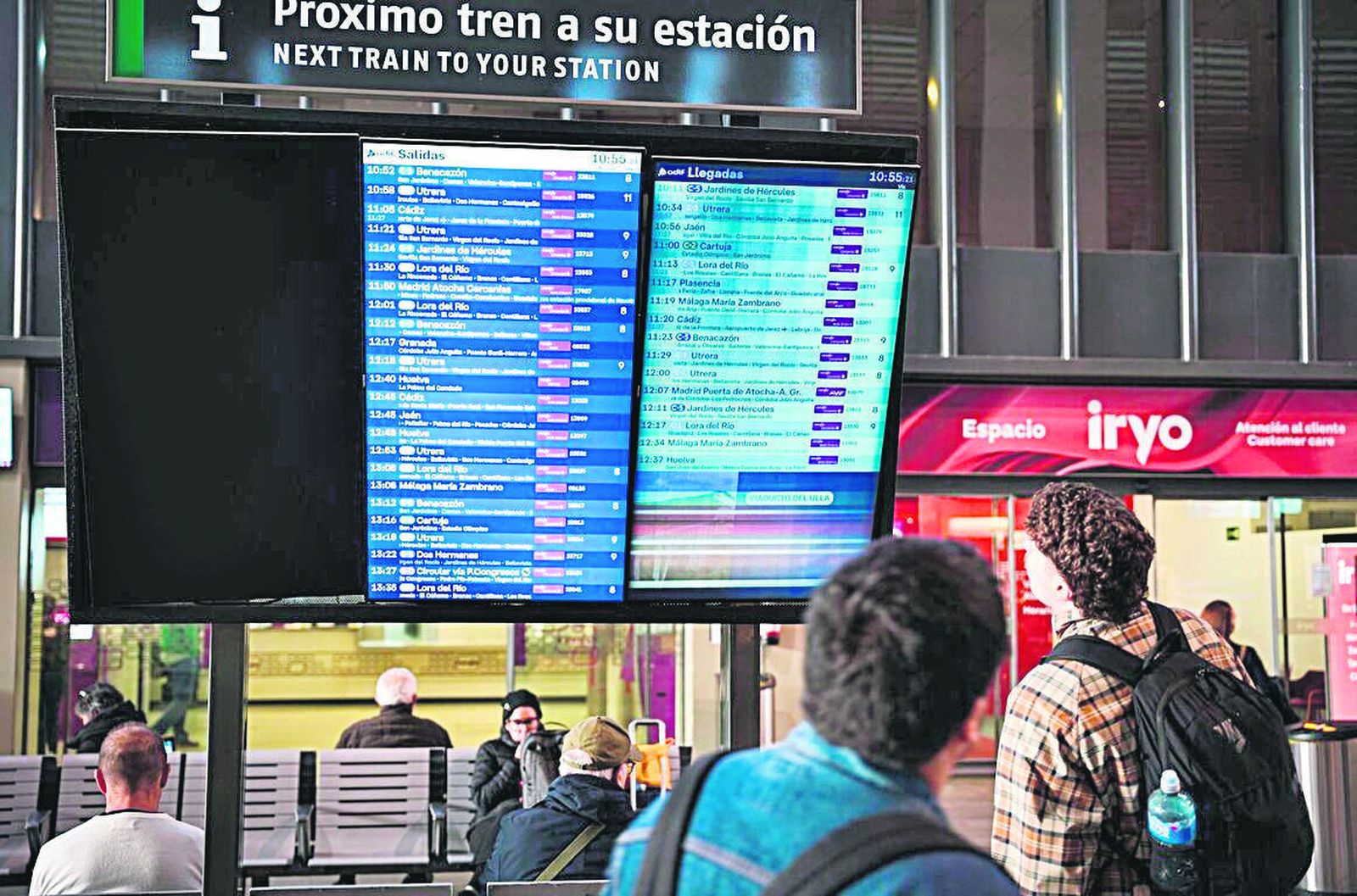 Unos viajeros consultando los trenes de cercanías y media distancia en la estación de Santa Justa.