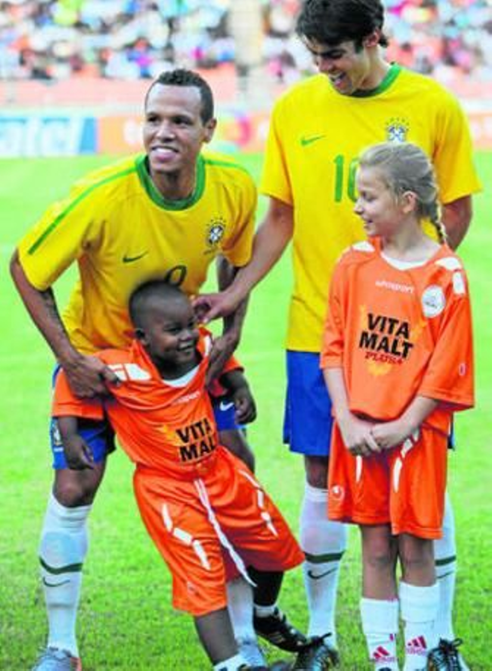 Luis Fabiano bromea con un niño, junto a Kaká, antes del último amistoso de Brasil, en Tanzania.