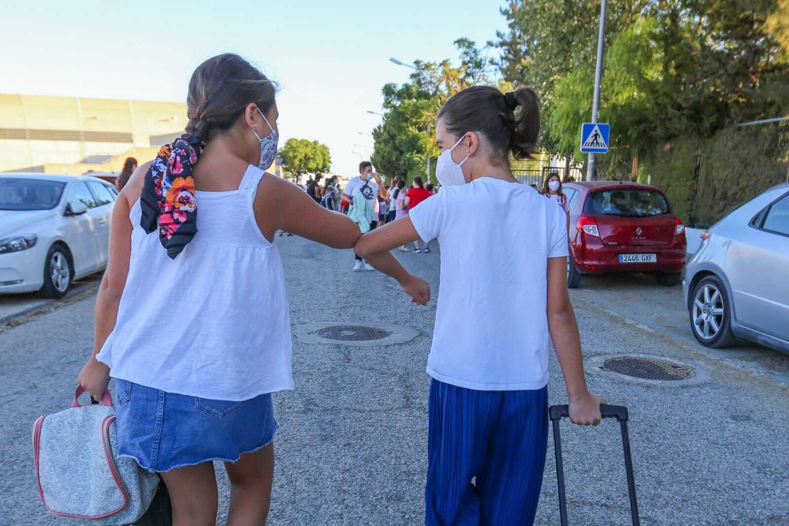 Dos alumnas del colegio Giner de los Ríos se saludan con el codo en la entrada del colegio.
