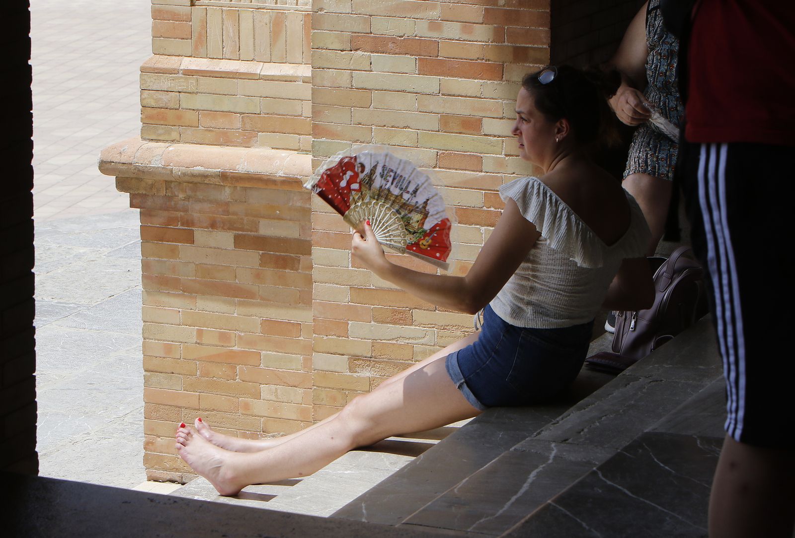 Una mujer se refresca con un abanico.