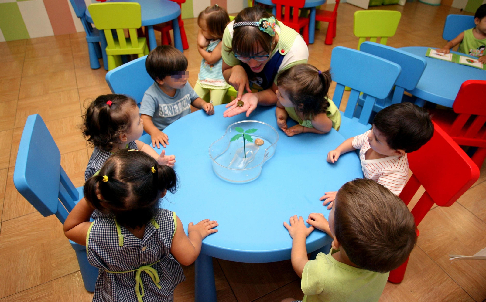 Varios niños con su educadora en una escuela infantil.