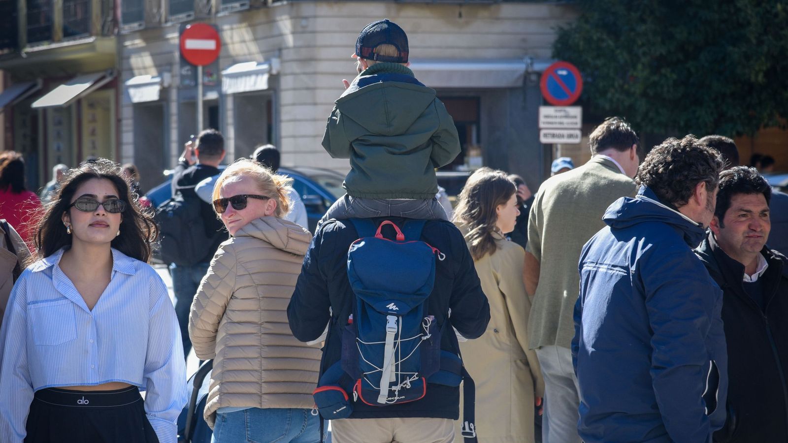 Padres pasean con su hijo sobre los hombros por el centro de la ciudad.