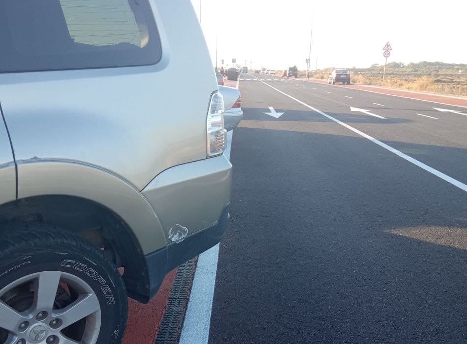 Vehículos aparcados en batería en la carretera de la playa de Camposoto.