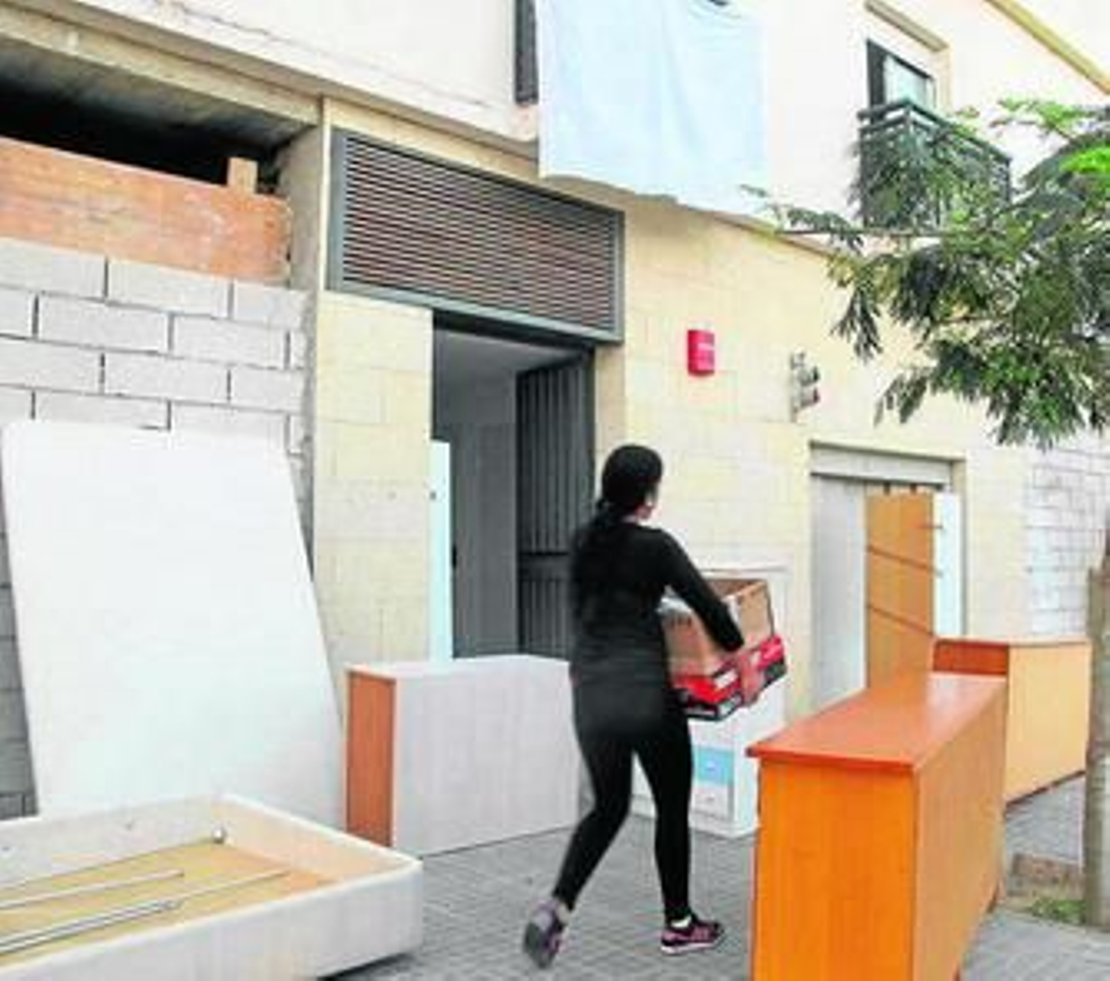 Una mujer introduce muebles en el edificio recién ocupado.