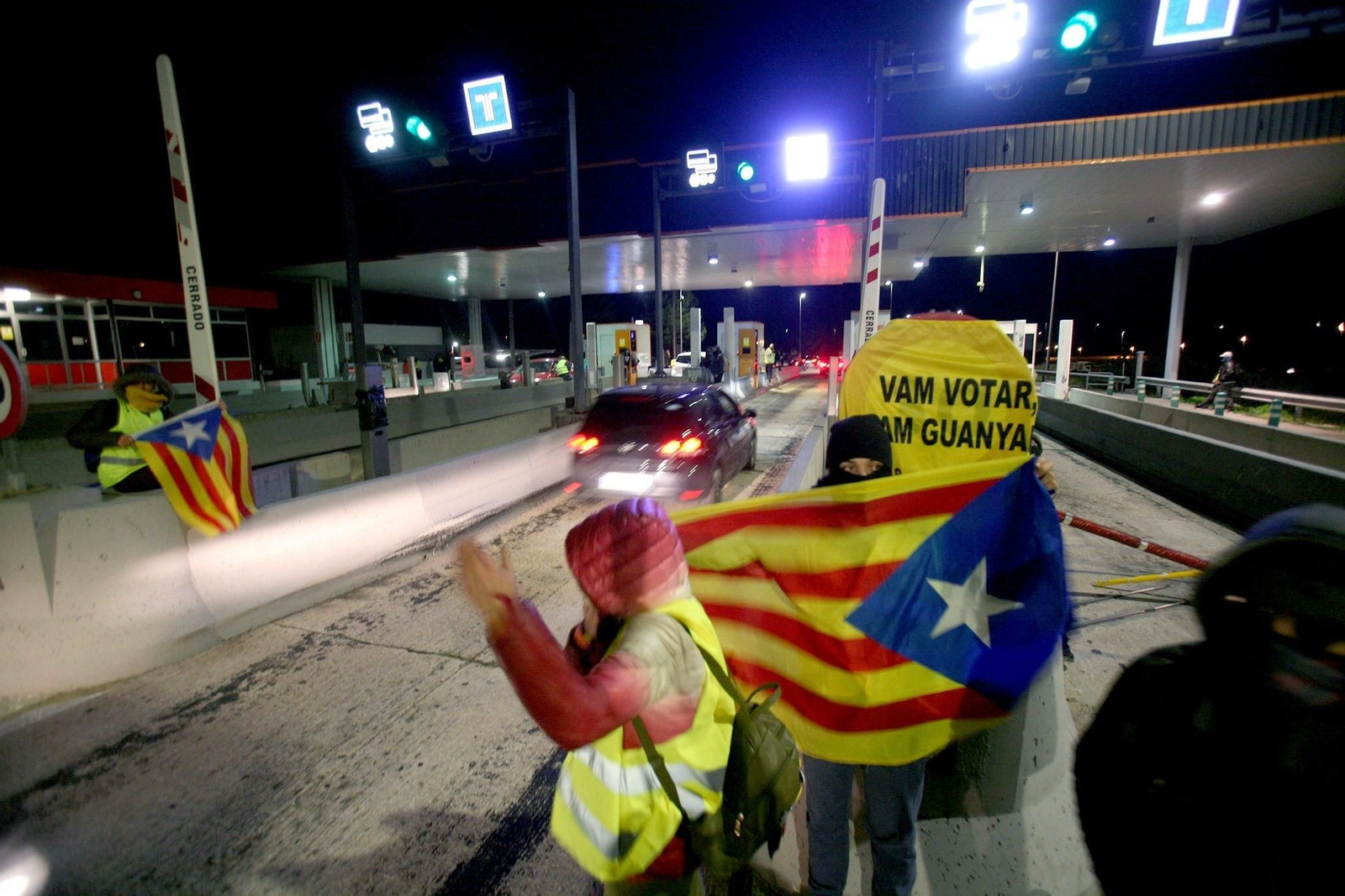 Un grupo de miembros de los Comités de Defensa de la República (CDR) levantando el domingo por la noche las barreras en la salida de la AP-7 en el peaje de L'Hospitalet de L'Infant.