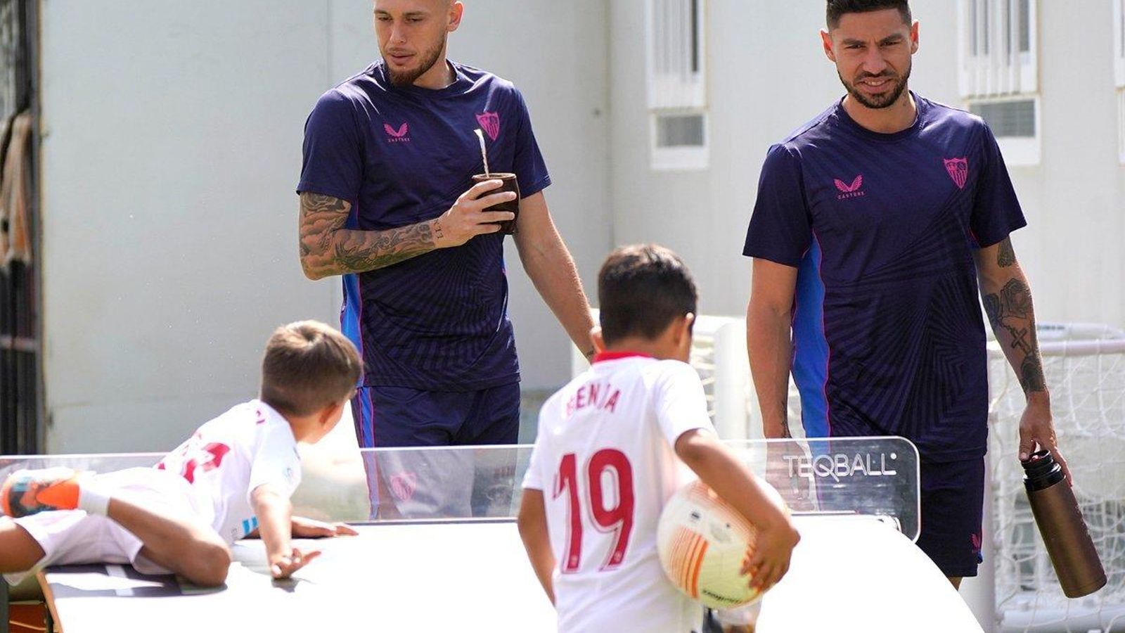 Ocampos y Montiel pasan junto a dos pequeños aficionados en la ciudad deportiva.