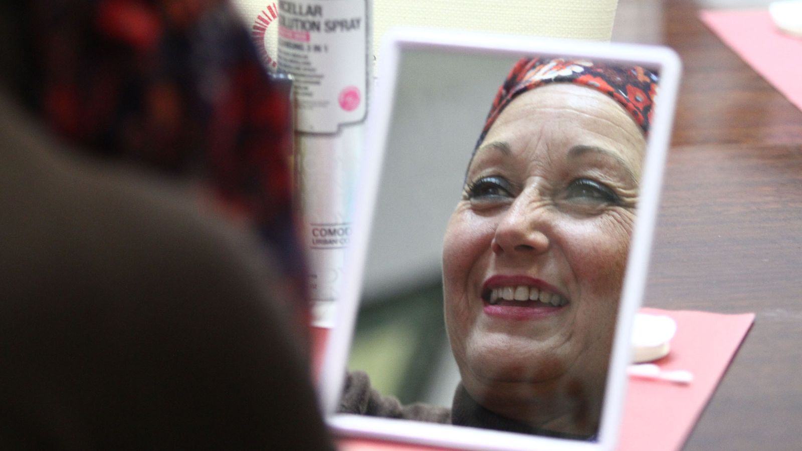 Una mujer se mira en el espejo durante el taller de maquillaje.