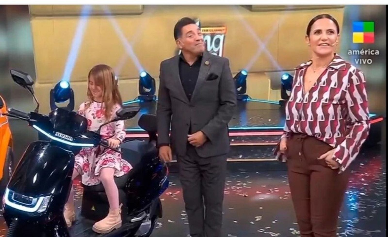 El presentador junto al ciclomotor eléctrico que se puso en marcha, con una niña a bordo