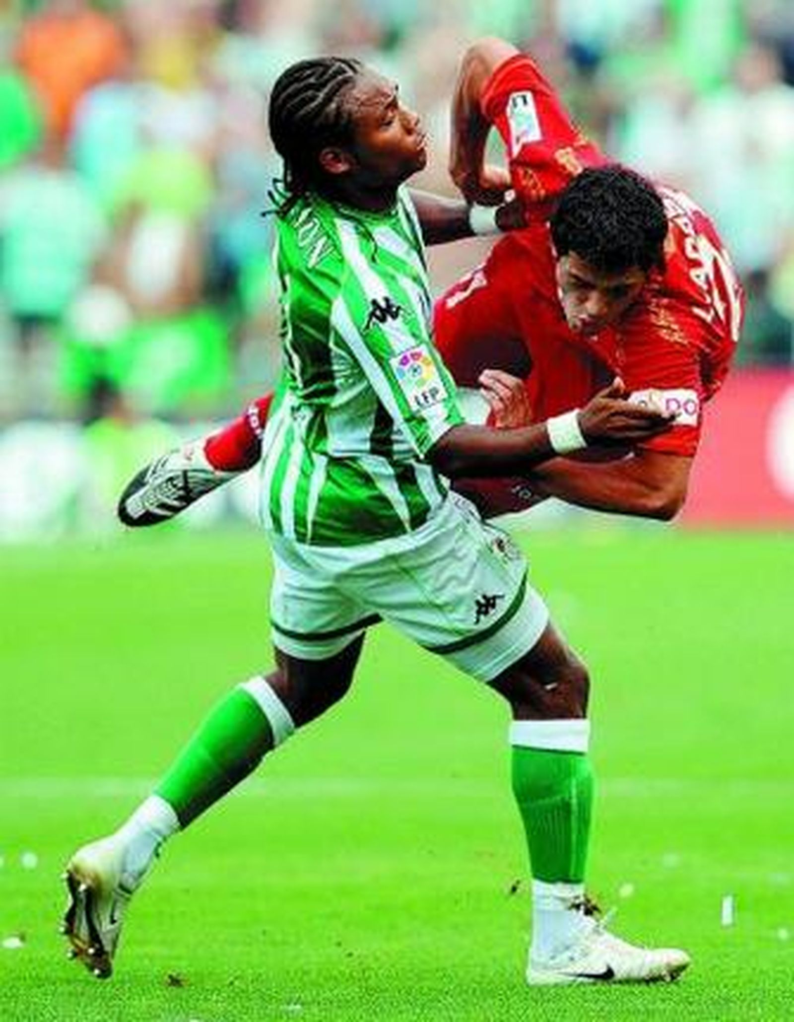 Acosta (Sevilla) vuela tras un choque con Nelson (Betis).