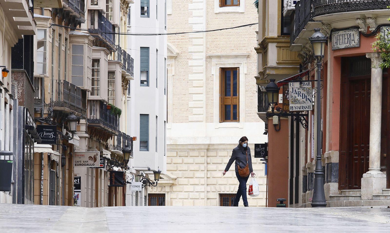 Una joven con una bolsa de la compra y mascarilla, este sábado, en la calle Císter.