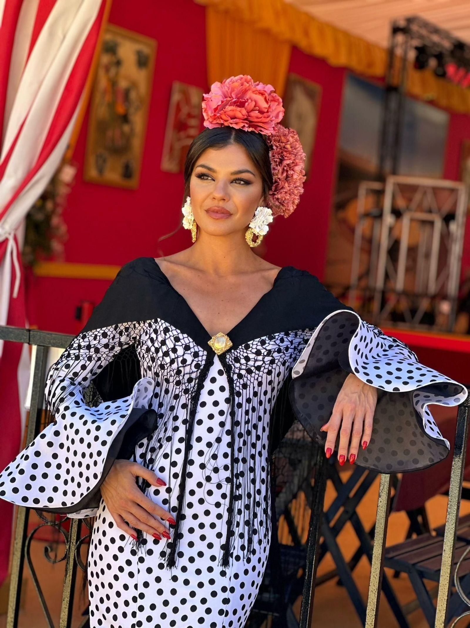Mia Crespo con un traje de flamenca blanco con lunares negros y las mangas largas.
