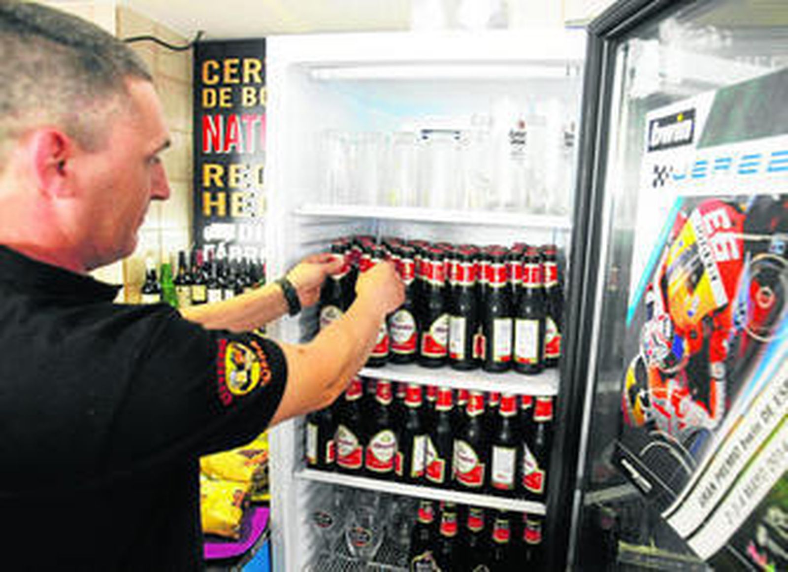 Un camarero aprovisiona una nevera con cervezas en un céntrico establecimiento de Jerez.
