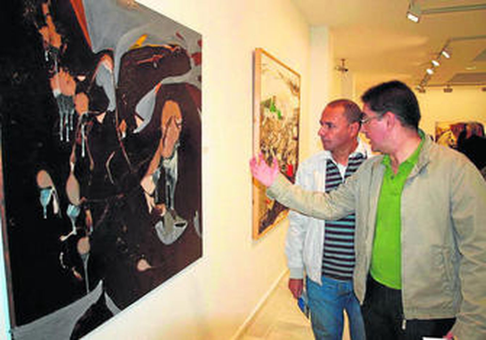 Una de las obras expuestas en la muestra de Nerva es comentada por dos asistentes.