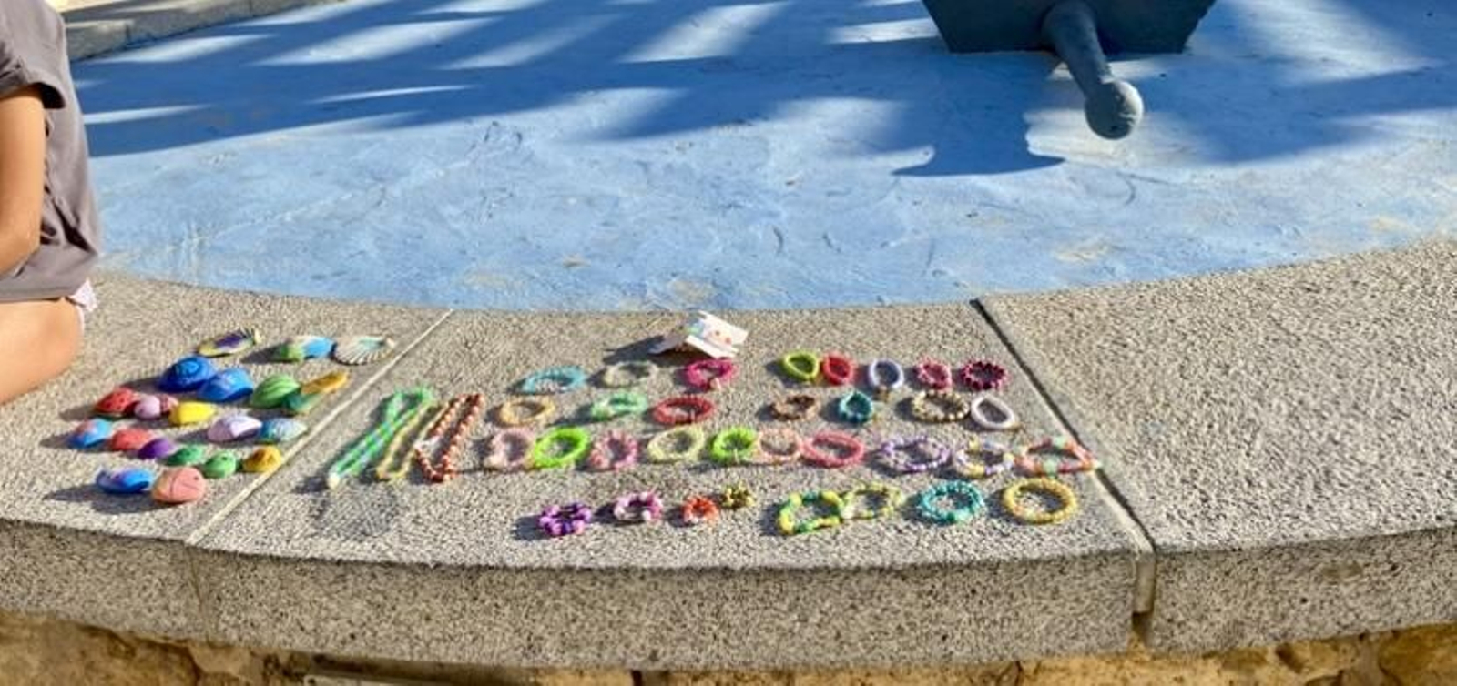 Un puesto infantil de venta de pulseras, collares y conchas en el paseo marítimo de una playa de Huelva.