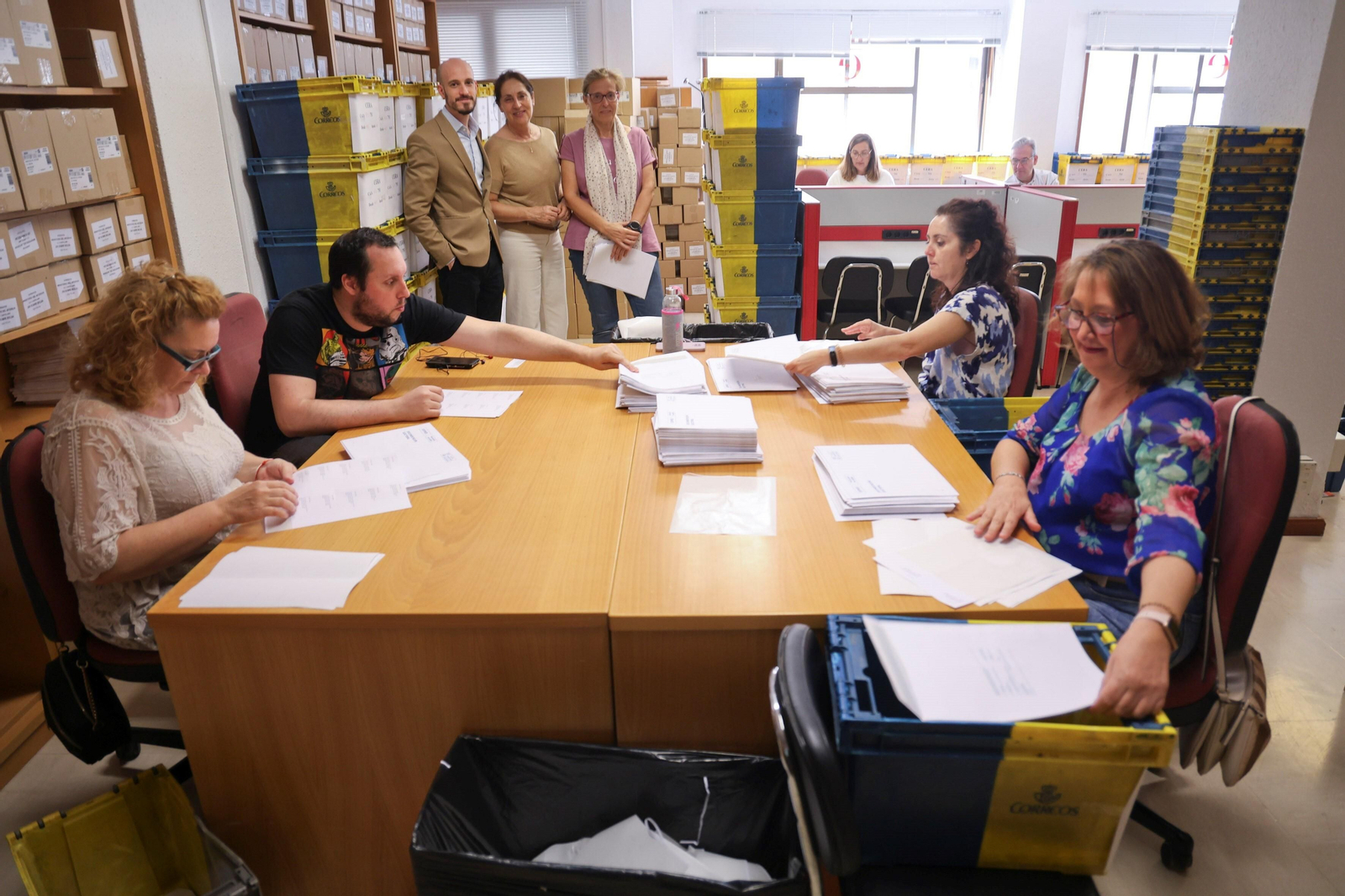 El delegado del INE y la jefa de la OCE (centro) junto a empleados que preparan los sobres para el voto por correo.