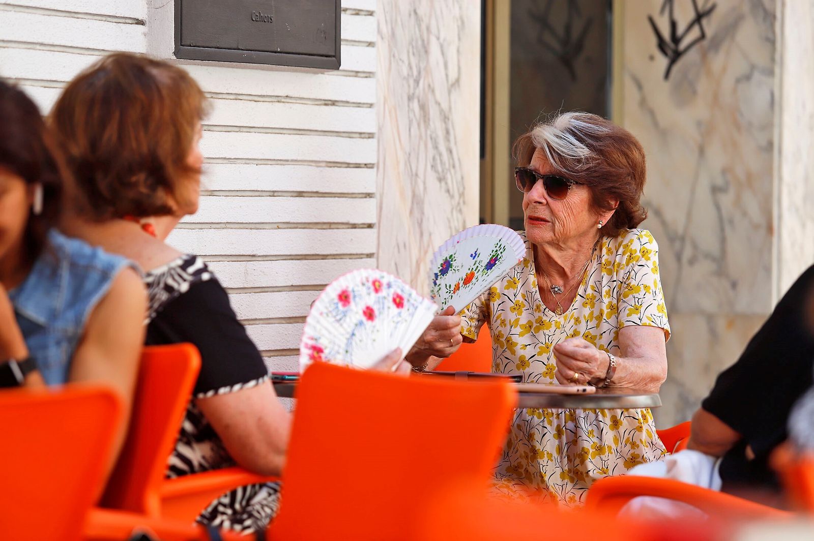 Dos mujeres charlan mientras se abanican.