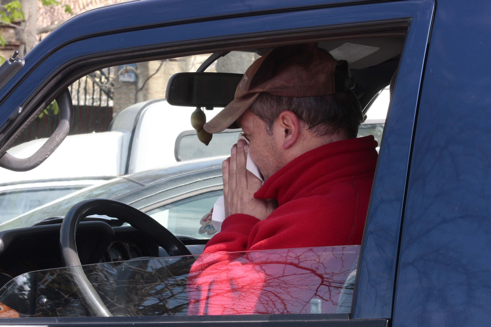 Un hombre se suena los mocos en el interior de un vehículo.