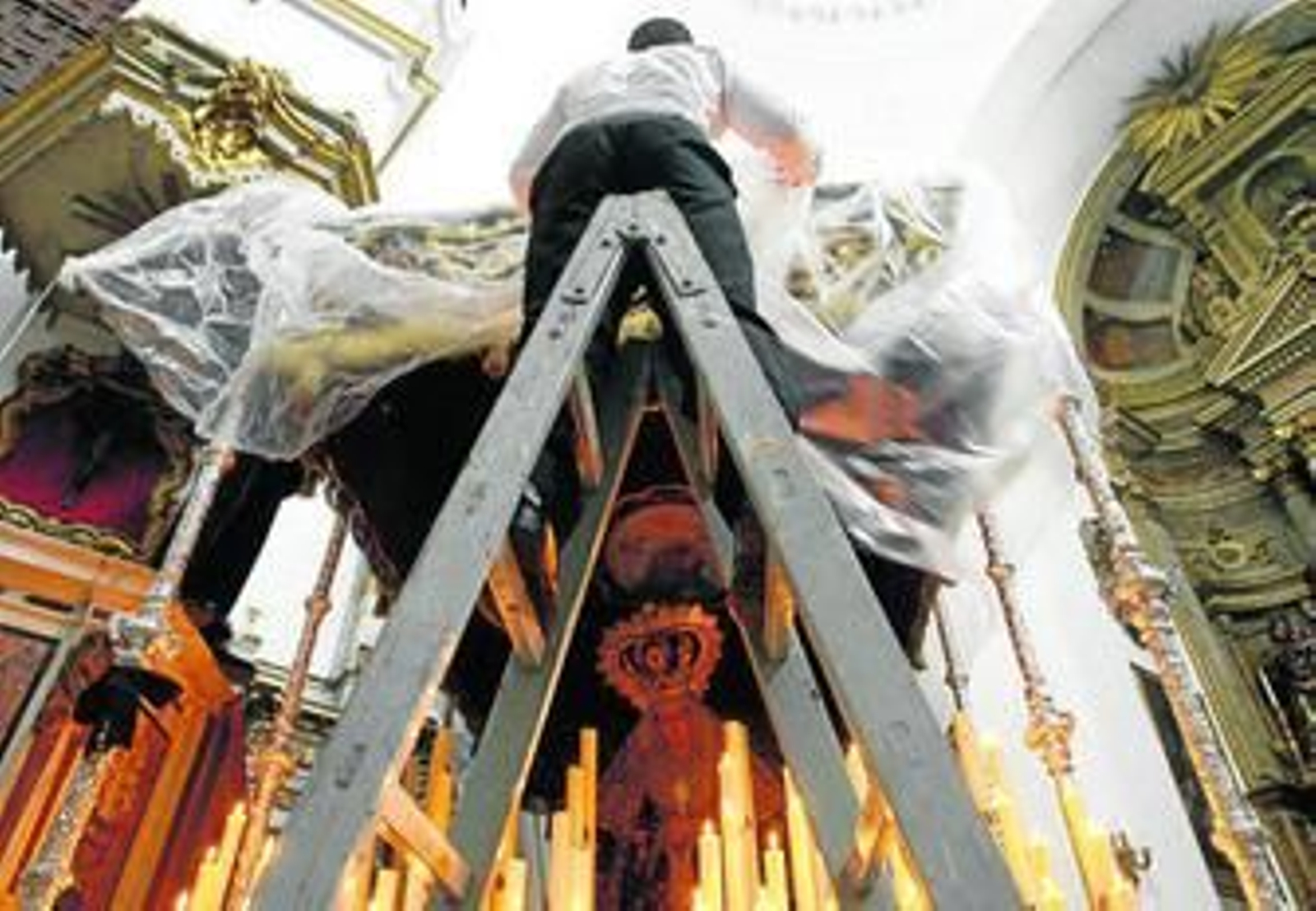 Un cofrade coloca un plástico para proteger de la lluvia el palio de Columna, en una imagen de archivo.