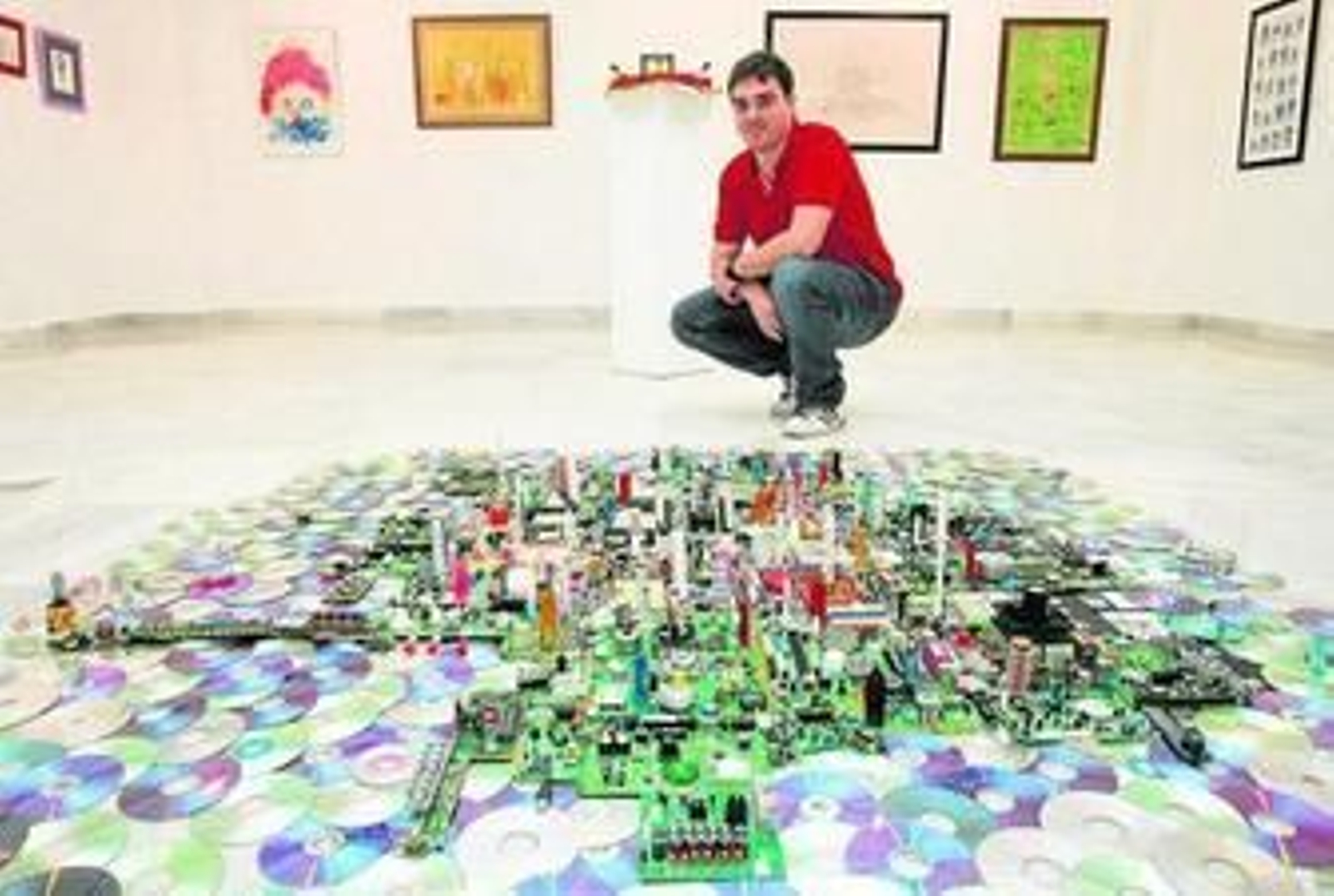 José Luis Ruiz junto a la ciudad que ocupa el centro de la sala, todo hecho con materiales de desecho.