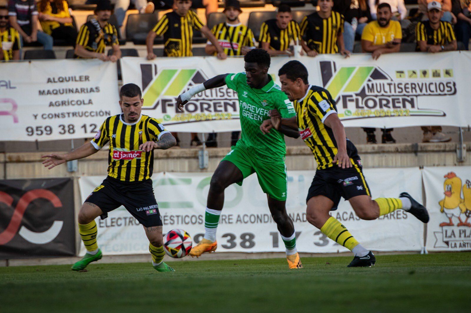 El bético Assane trata de avanzar con el balón controlado entre dos rivales.