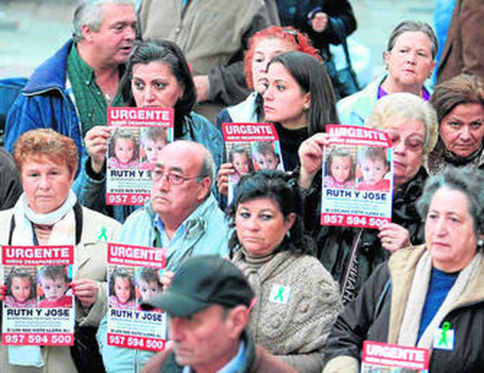 Varias personas portan carteles de los niños durante una concentración de apoyo realizada en Huelva.