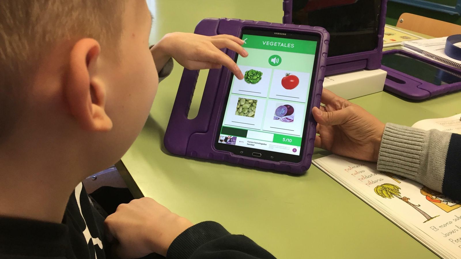 Dos hermanos ucranianos trabajan el idioma con un dispositivo electrónico.