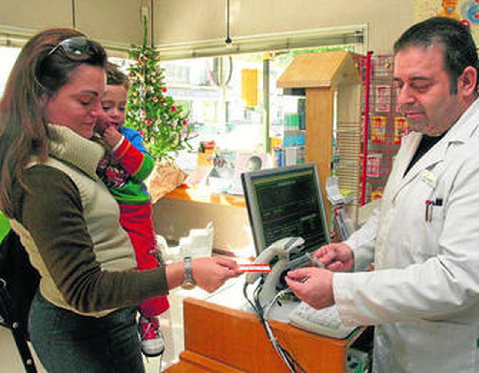 Una mujer ofrece la tarjeta sanitaria en una farmacia de Campanillas, en Málaga.