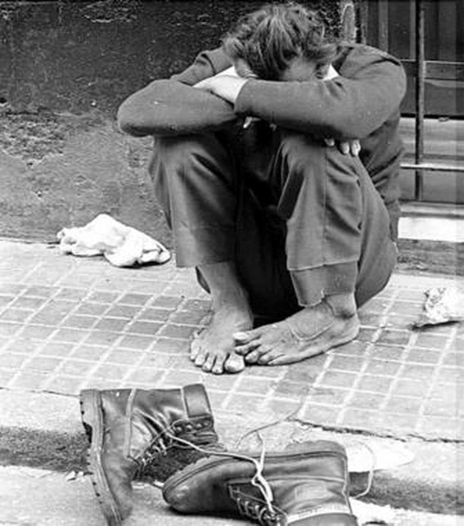 Un indigente sentado en la calle.
