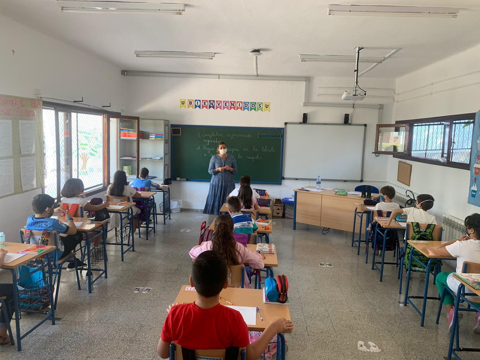 Una profesora imparte clase a sus alumnos con mascarilla.