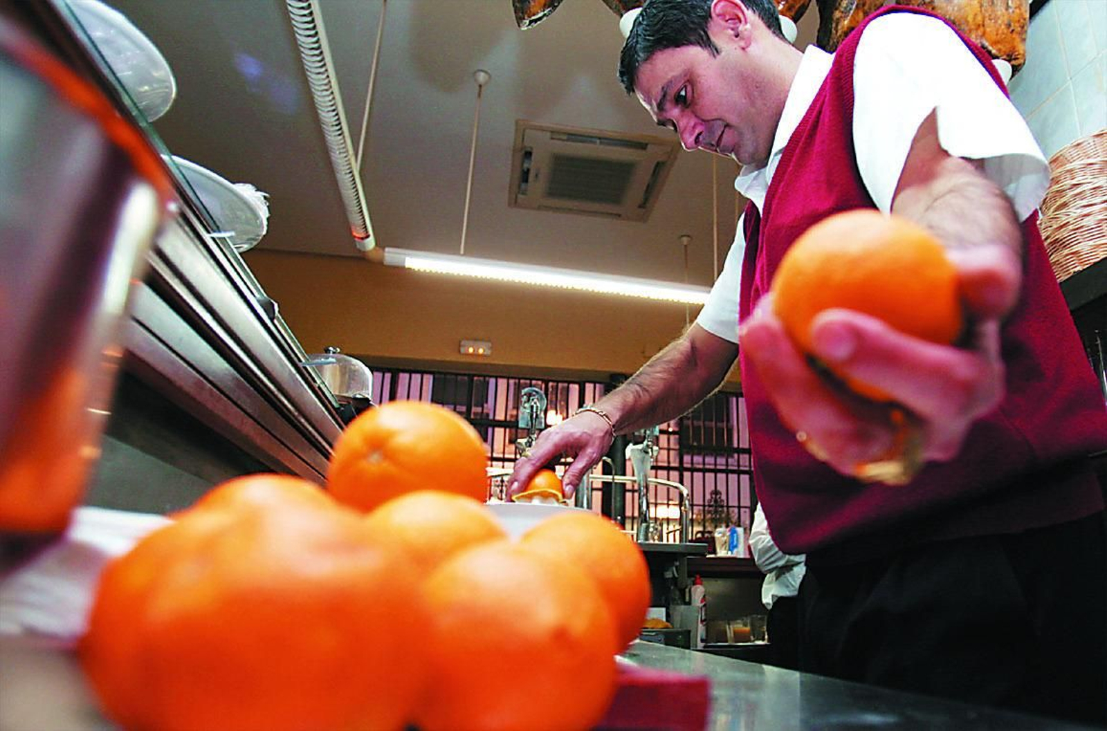 Un camarero prepara un zumo de naranja en un establecimiento
