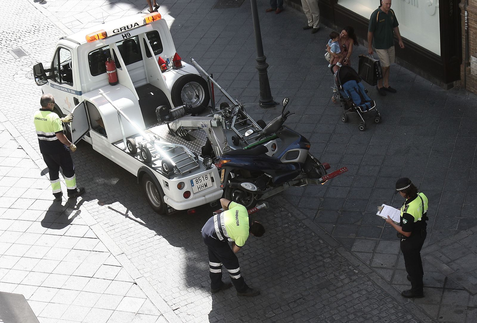 La grúa municipal retira una moto aparcado ante la presencia de la Policía Local, en una imagen de archivo