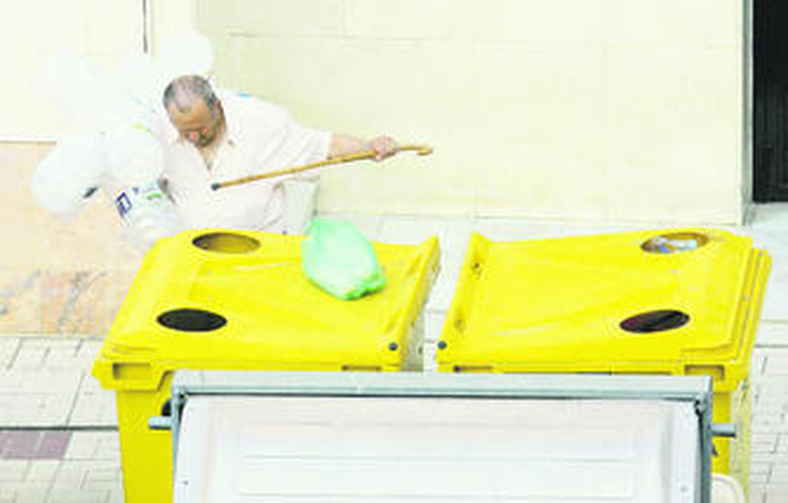 Un anciano deposita botellas de plástico en un contenedor de reciclaje de envases en Málaga.