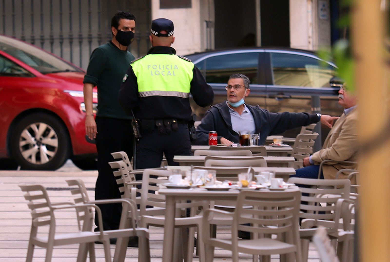 Un agente de la Policía Local de Huelva charla con varios ciudadanos en un bar.