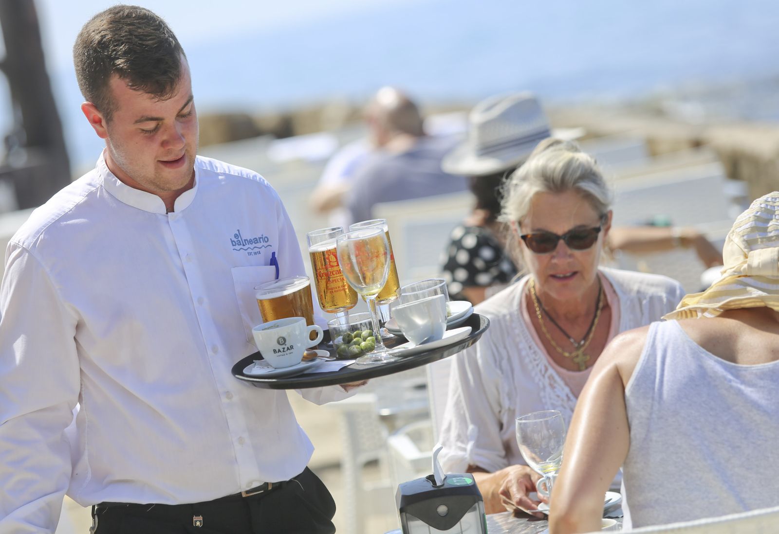 Un camarero sostiene una bandeja en una terraza de Málaga.
