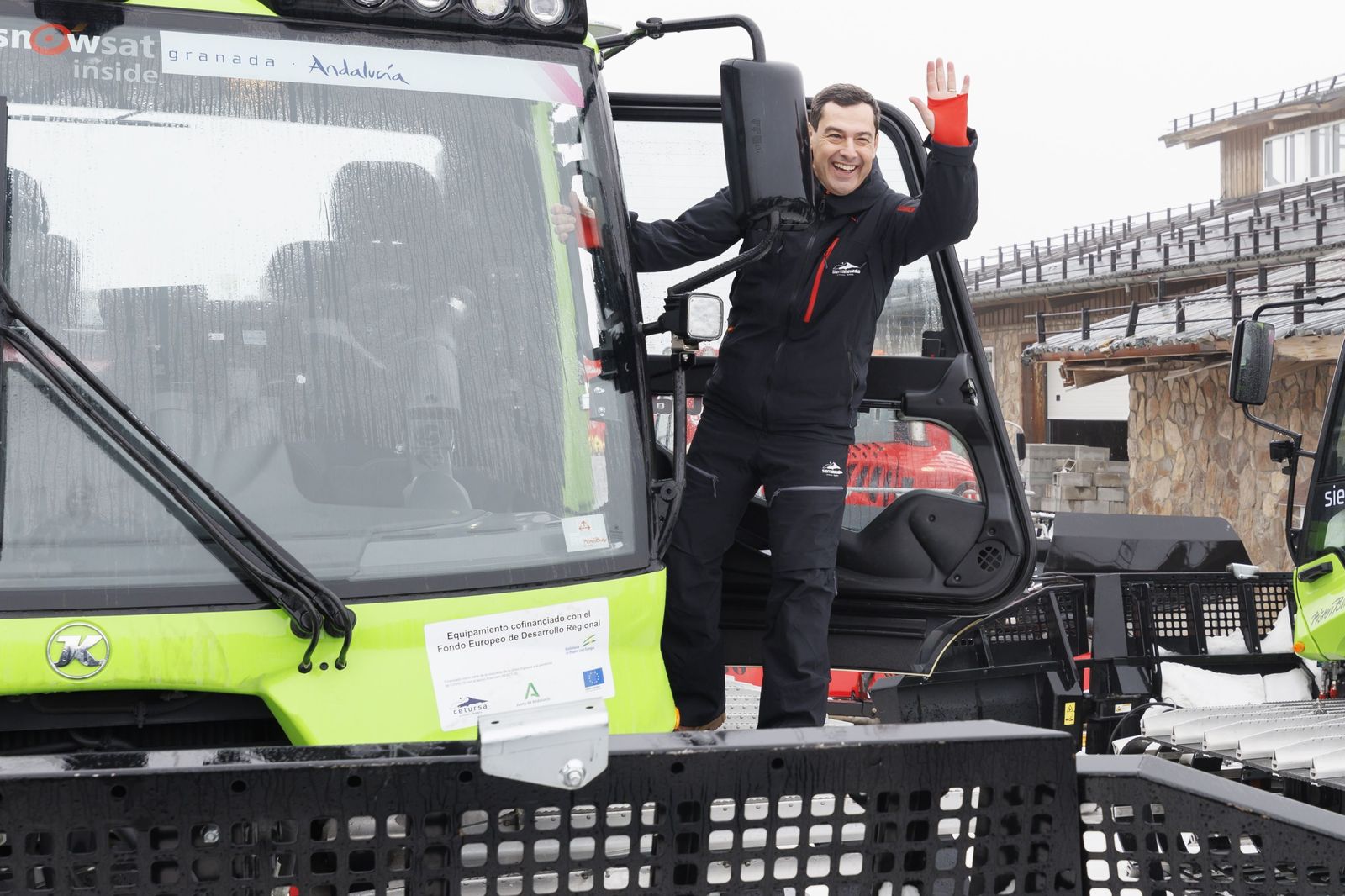 El presidente de la Junta de Andalucía, Juanma Moreno, saluda desde una máquina pisapistas de Sierra Nevada