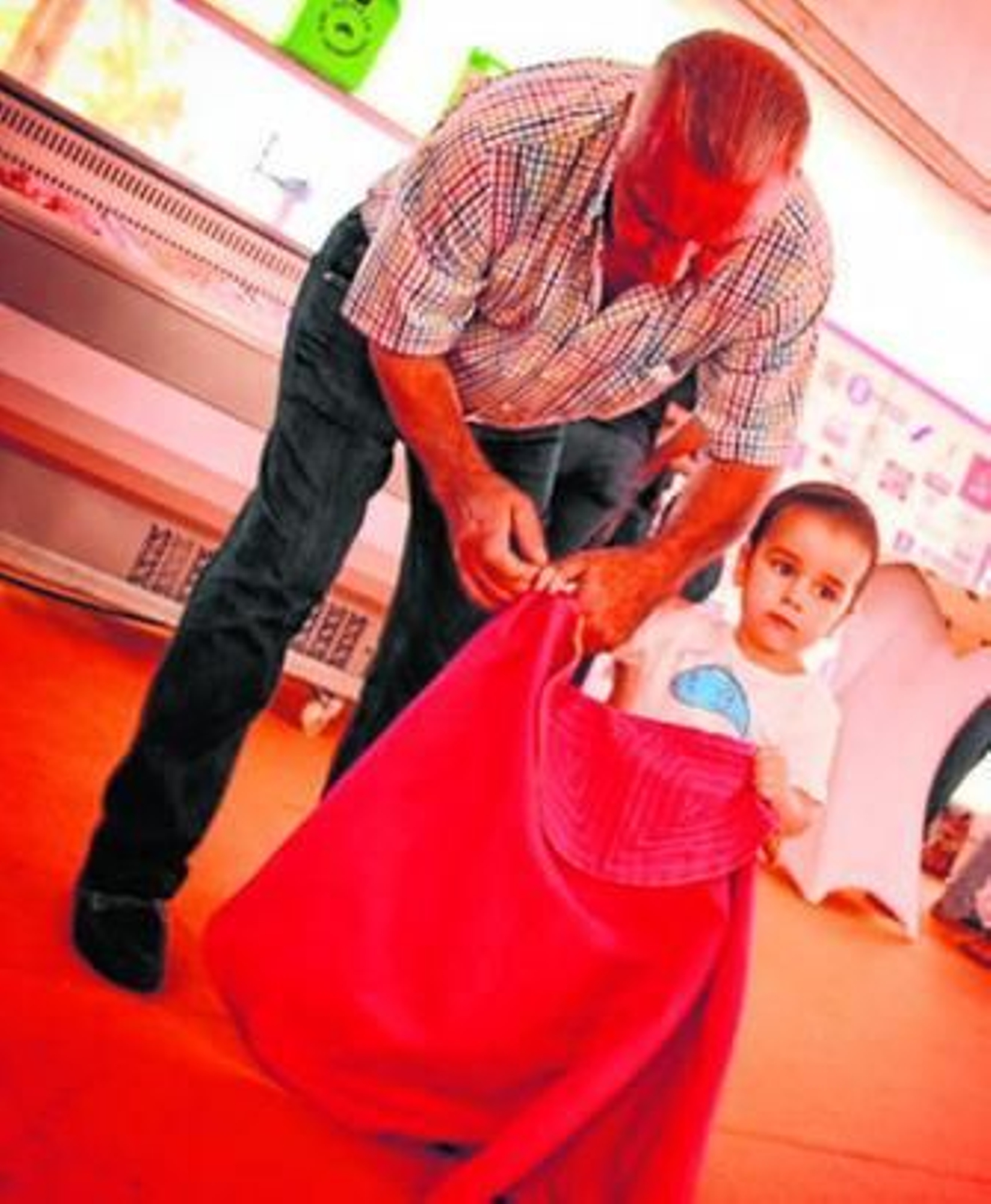Un hombre ayuda a un niño a coger el capote durante la exhibición de la escuela taurina Sevilla-Amate.