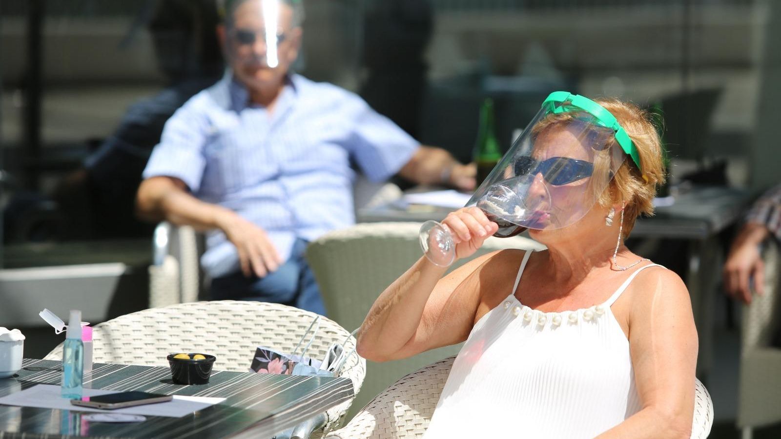 Una cliente, protegida con una visera, toma un refresco en Kaleido.