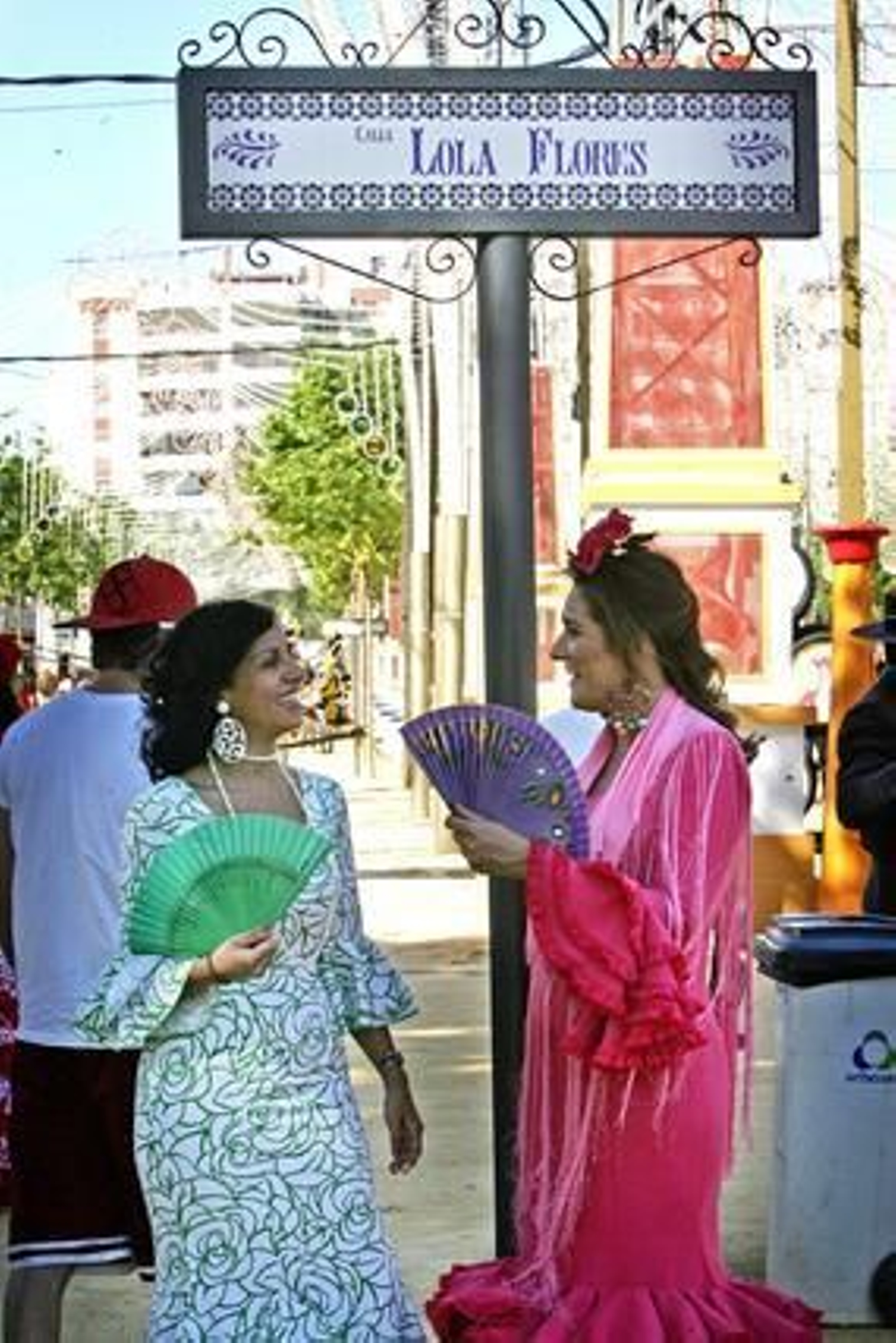 Dos guapas señoras vestidas de gitana conversan ante la señalización de la calle ‘Lola Flores’ en el Real.

Foto: Pascual