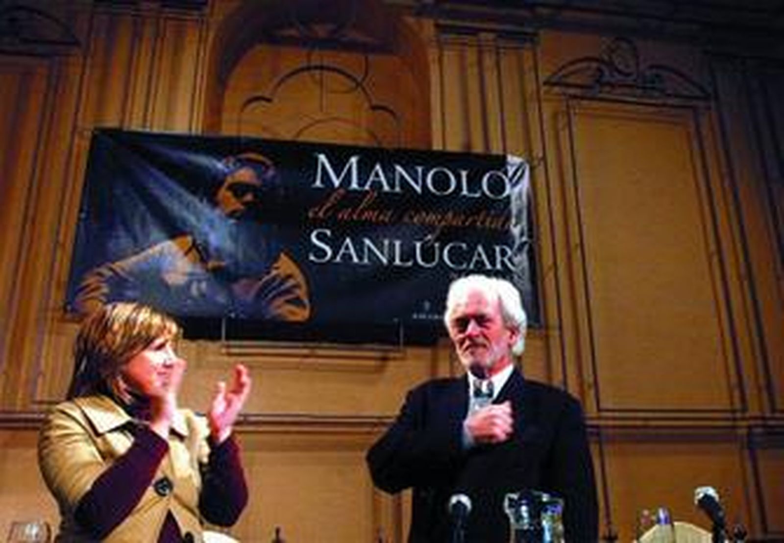 La alcaldesa Irene García aplaude al autor Manolo Sanlúcar tras la presentación de su primer libro.