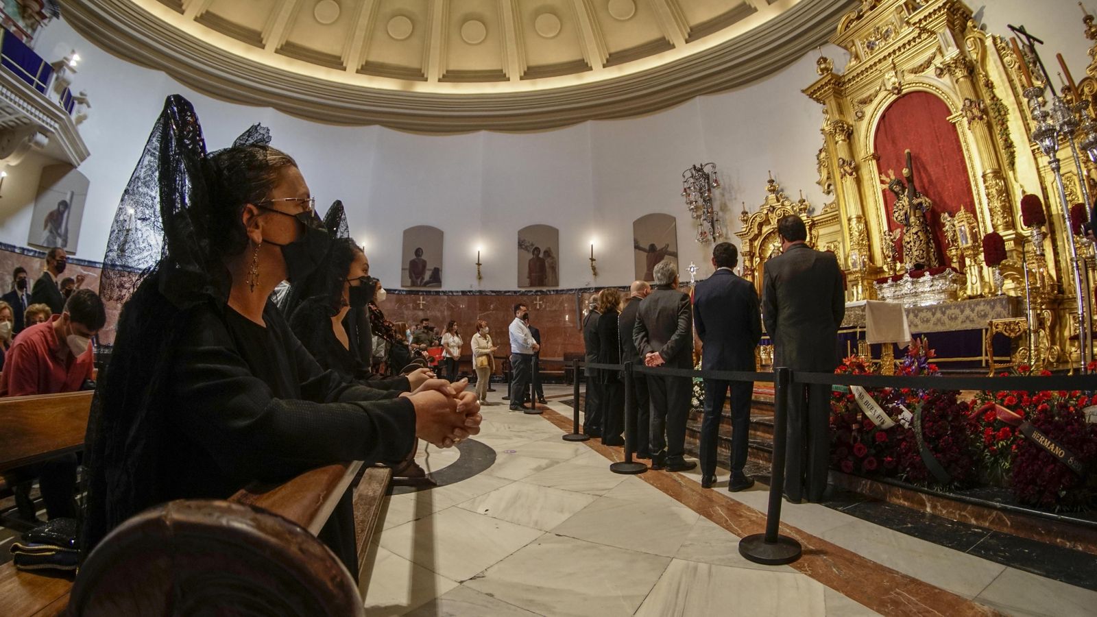 Varia mujeres de mantilla rezan ante el Señor del Gran Poder.