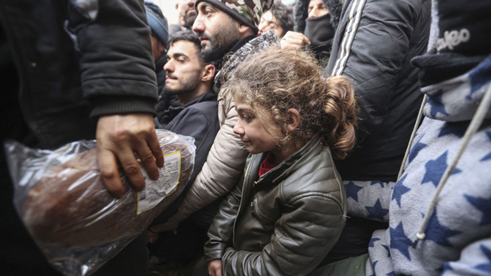 Una niña aguarda junto a otros migrantes en la línea fronteriza.