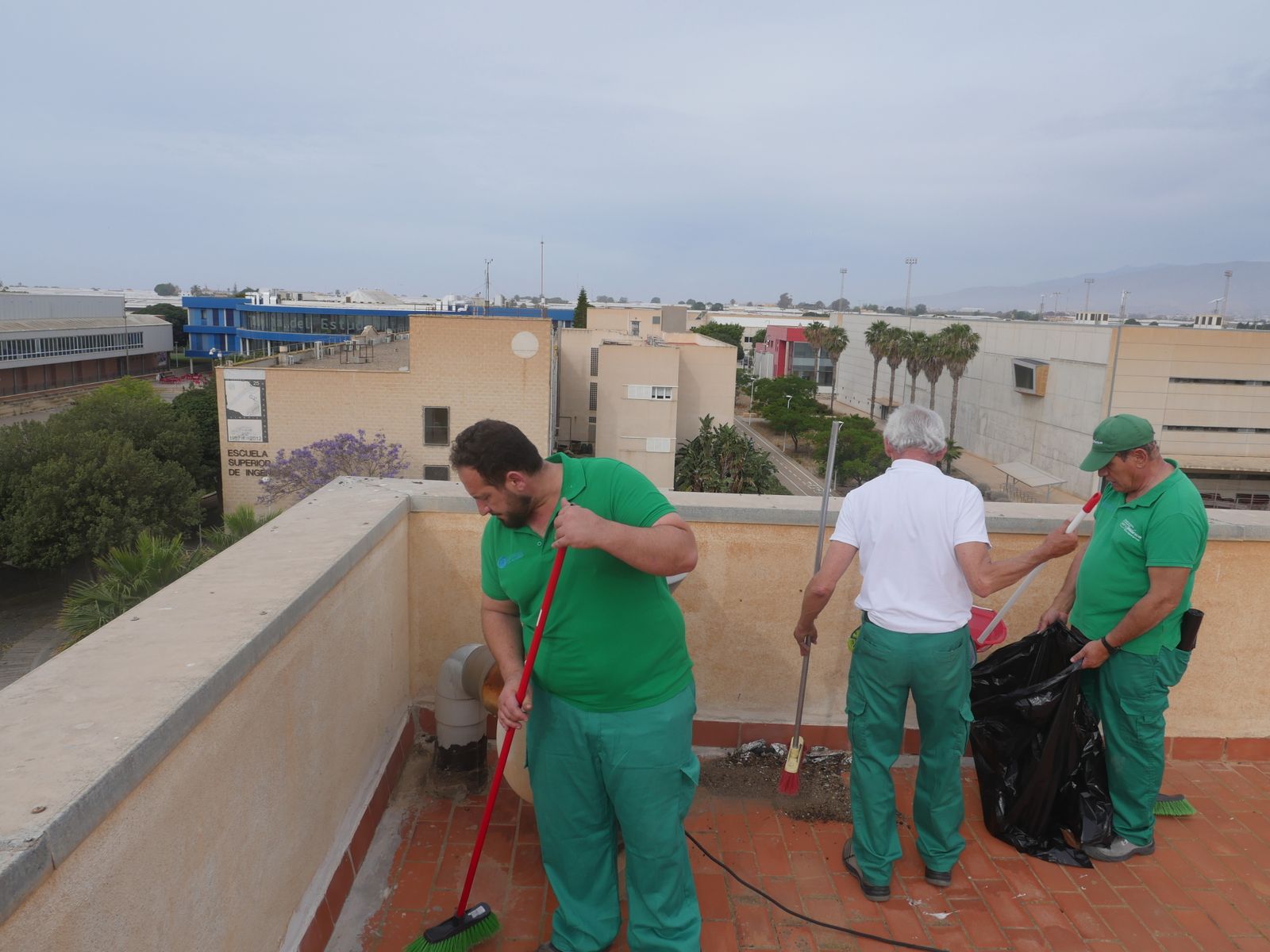 Operarios del servicio de limpieza de Verdiblanca retiran la hojarasca de una de las azoteas del campus.