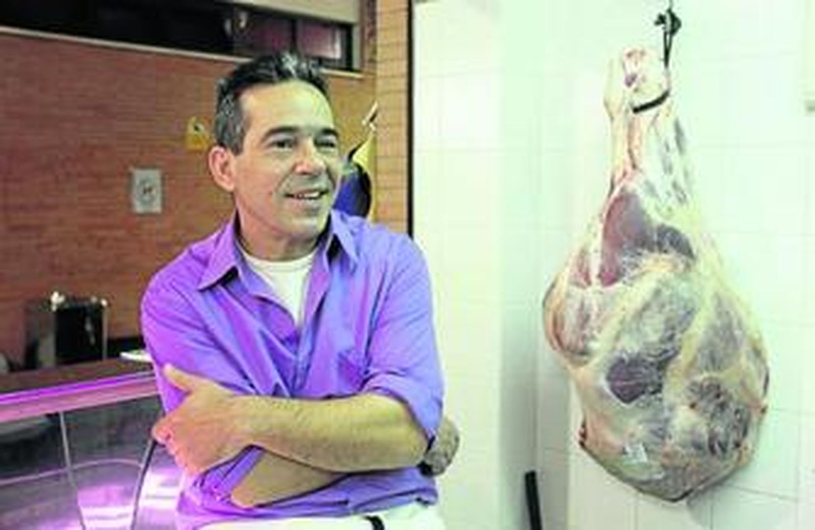 Antonio Ortega, en el puesto 13 del mercado de Triana, junto a uno de sus productos cárnicos.