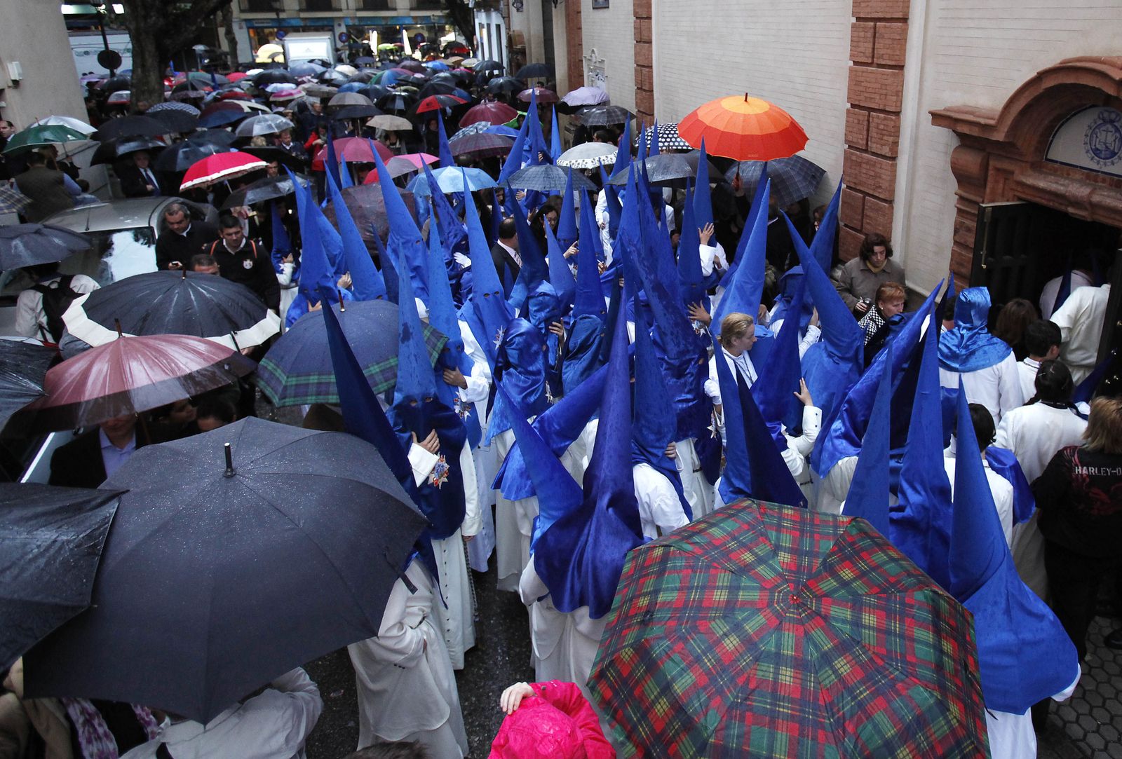 Nazarenos de la Hermandad de Montserrat entre un mar de paraguas.