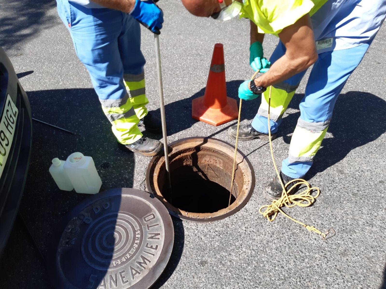 Dos operarios recogen muestras de agua en uno de los puntos de saneamiento.