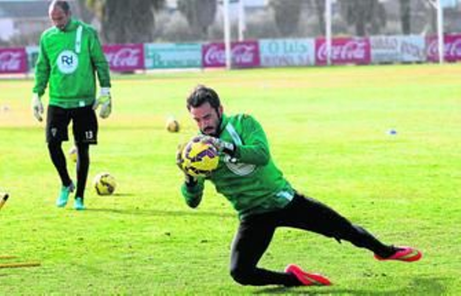 Juan Carlos atrapa un balón en un entrenamiento, con Mikel Saizar al fondo.
